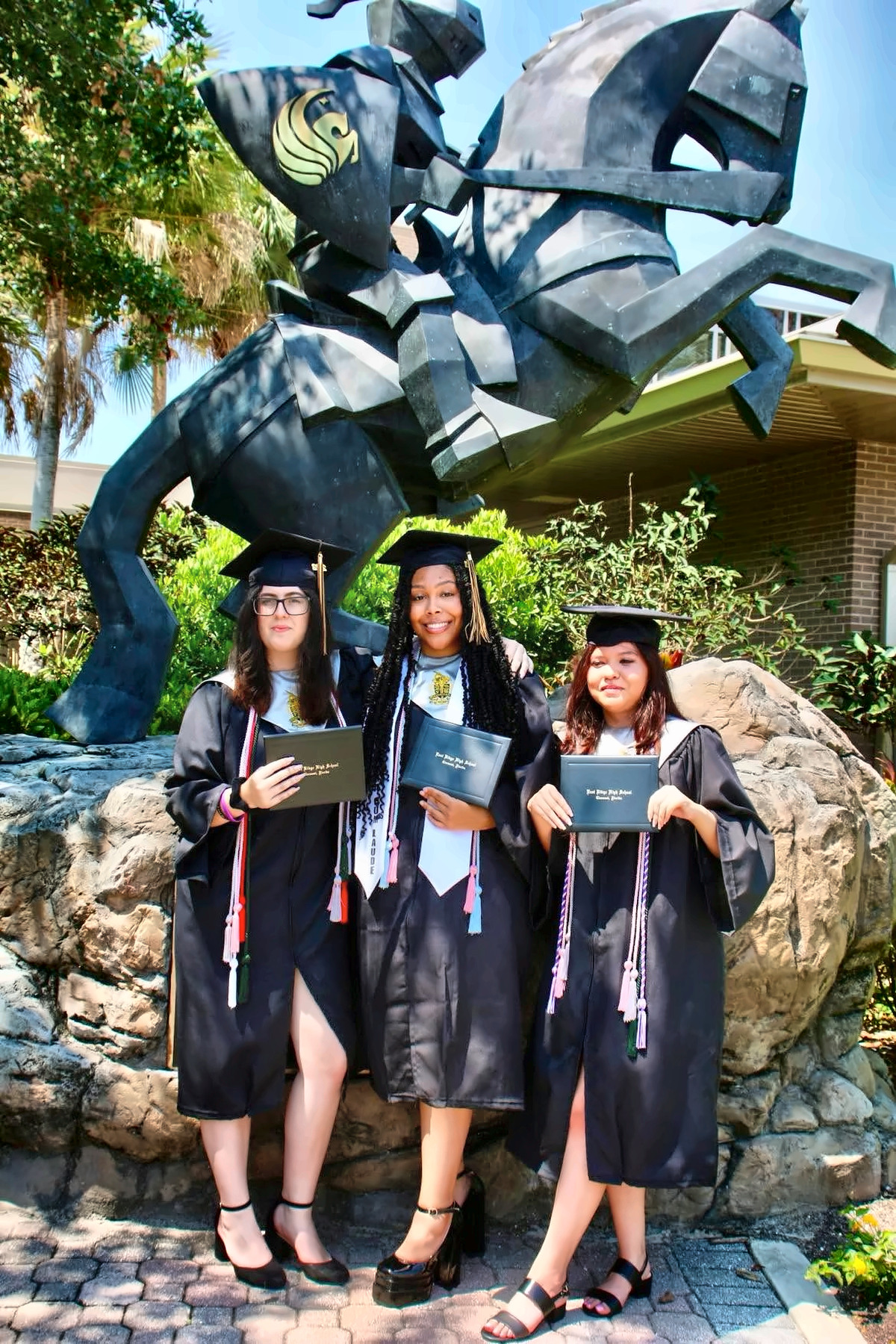 Three graduates posing with diplomas